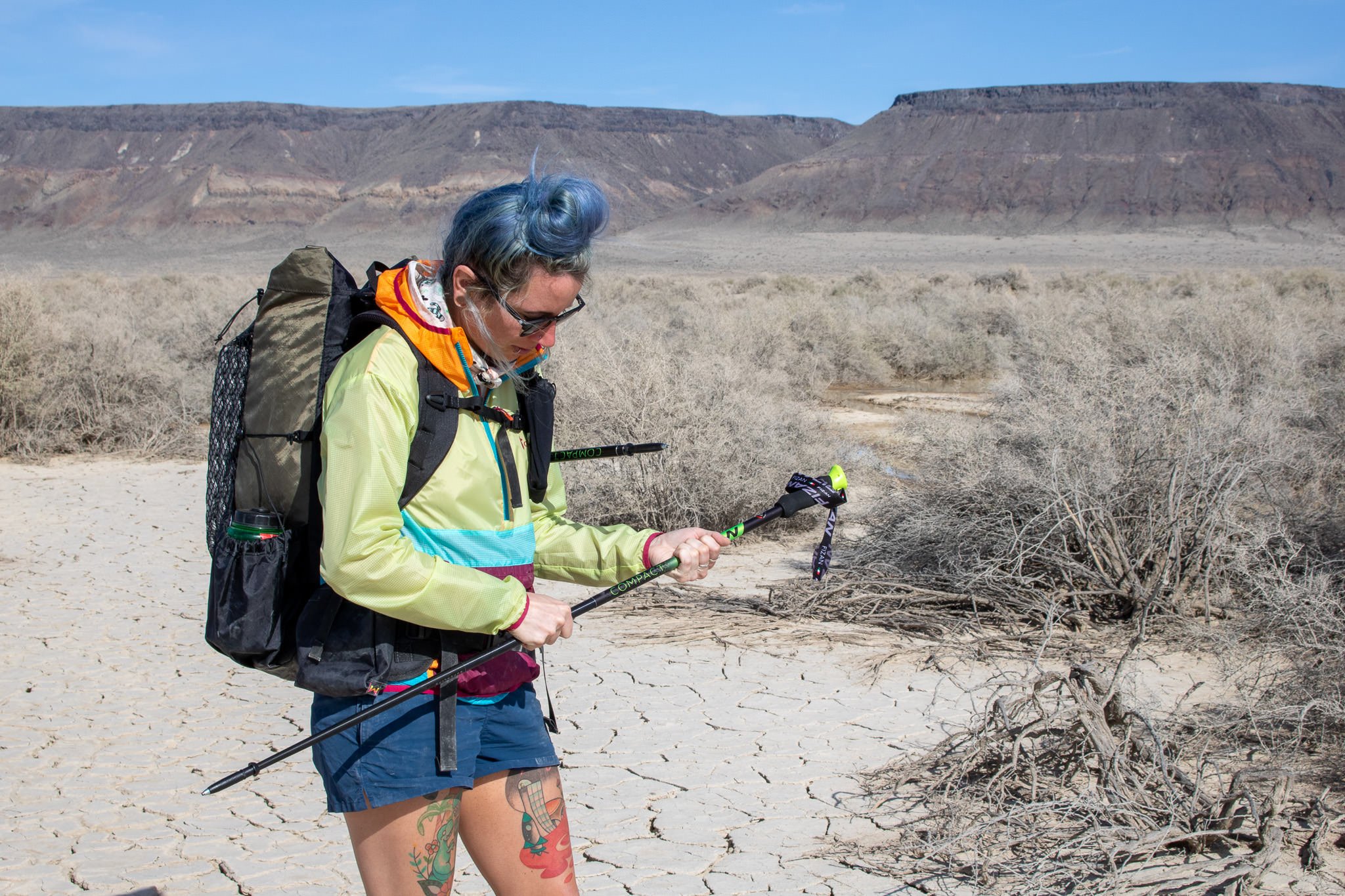 A hiker adjusting the Fizan Compact 3 trekking poles in the desert