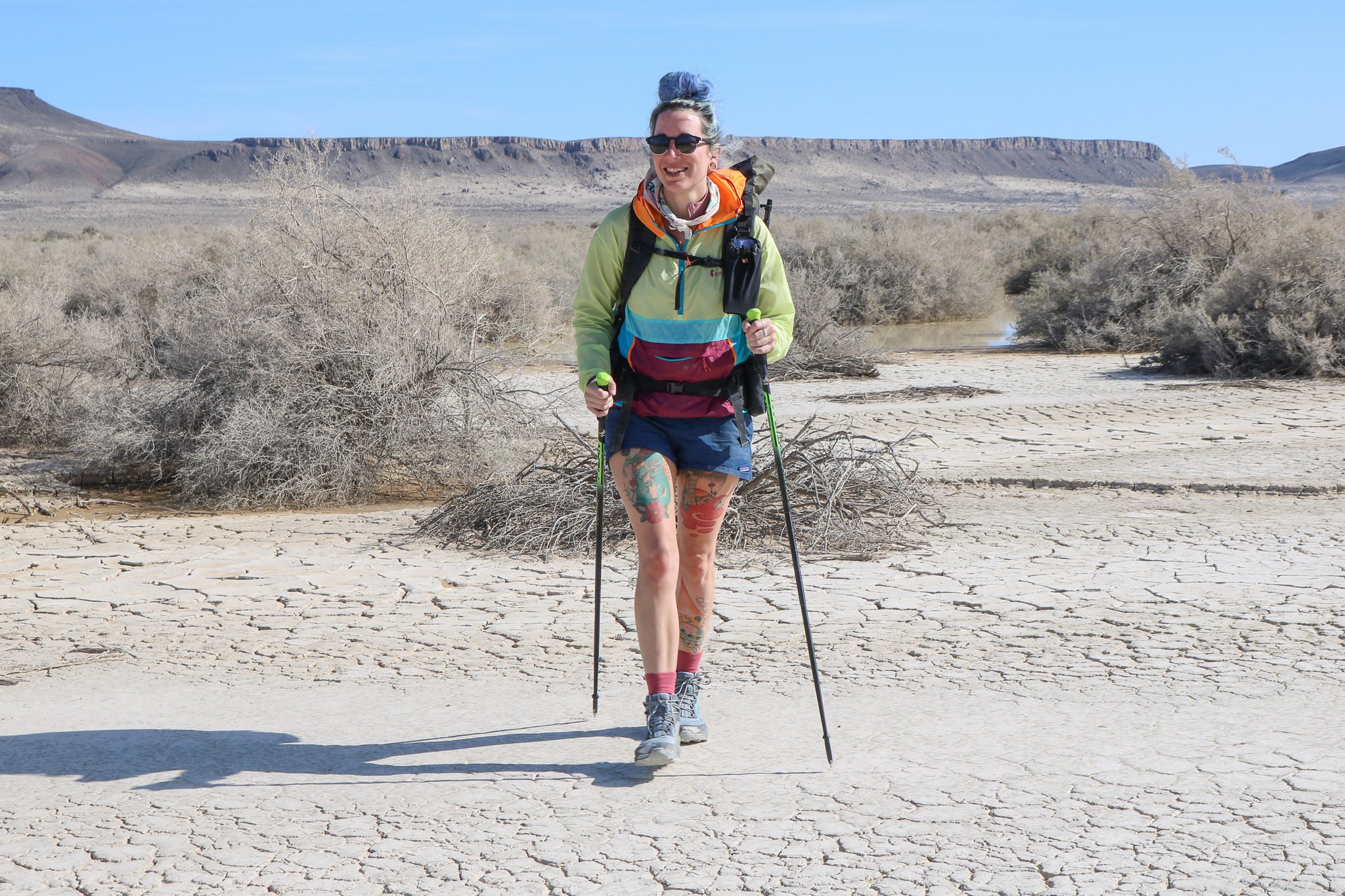 A backpacker wearing the Cotopaxi Teca Windbreaker in the breezy Alvord Desert