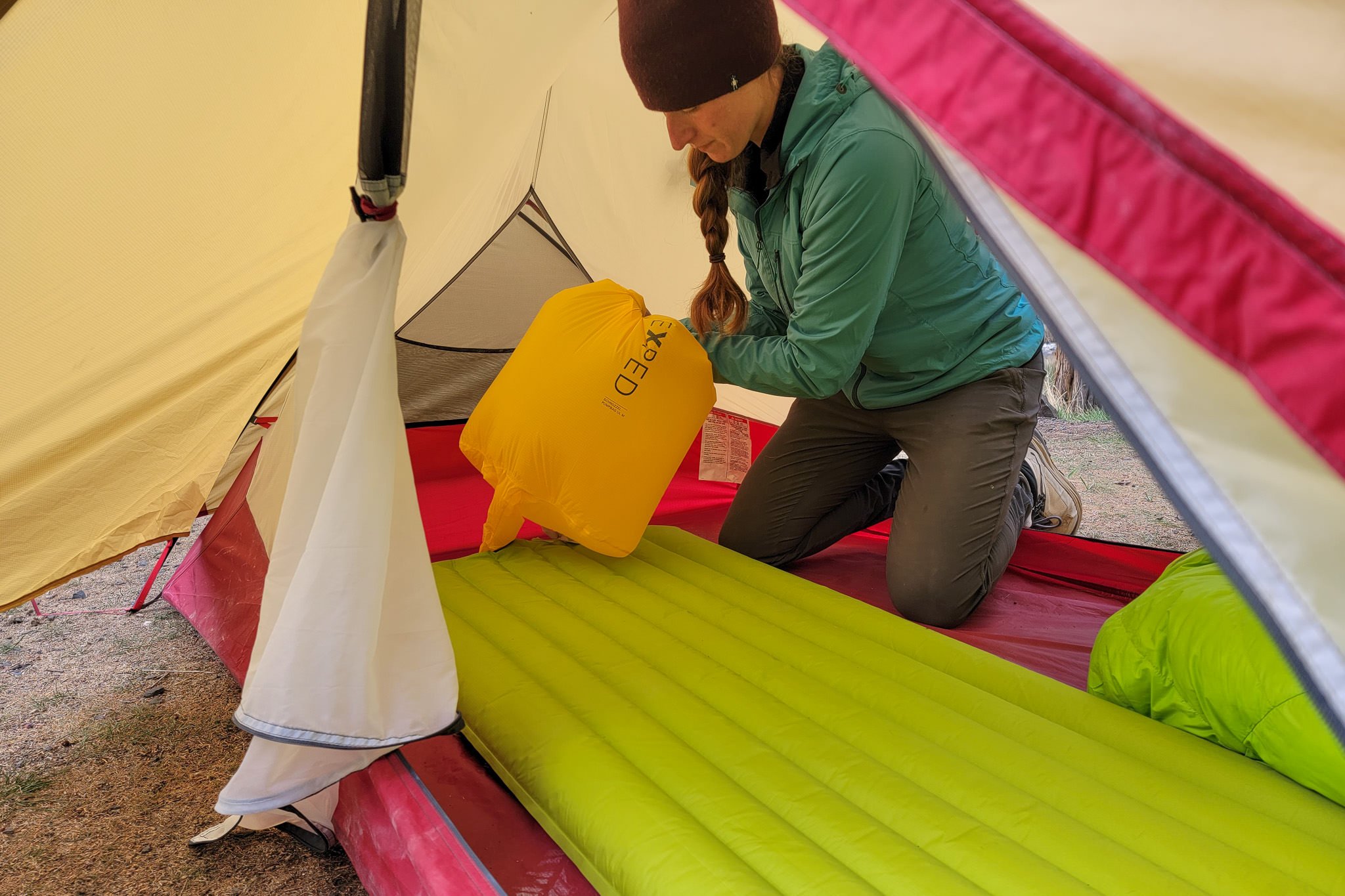 A backpacker using a pump sack to inflate a sleeping pad