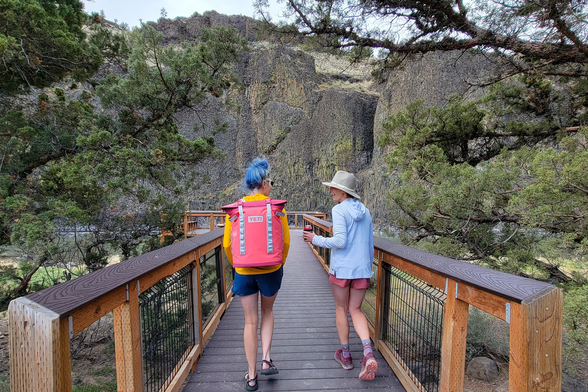 Two people wearing Patagonia Barely Baggies Shorts walking down a pier with a cooler