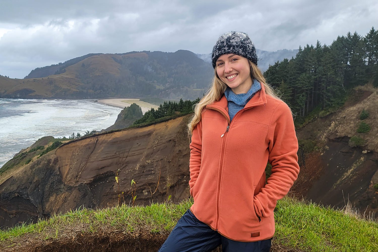 A hiker wearing the REI Groundbreaker Fleece 2.0 on a coastal bluff