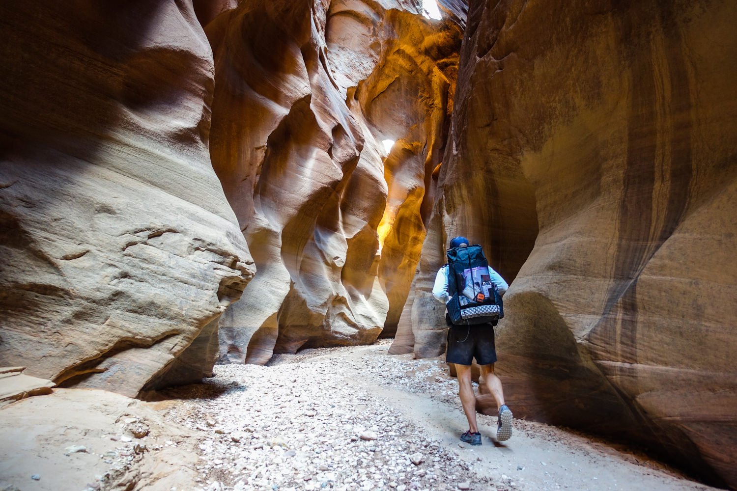 A hiker walking through a canyon in Nike Dri FIT Challenger shorts