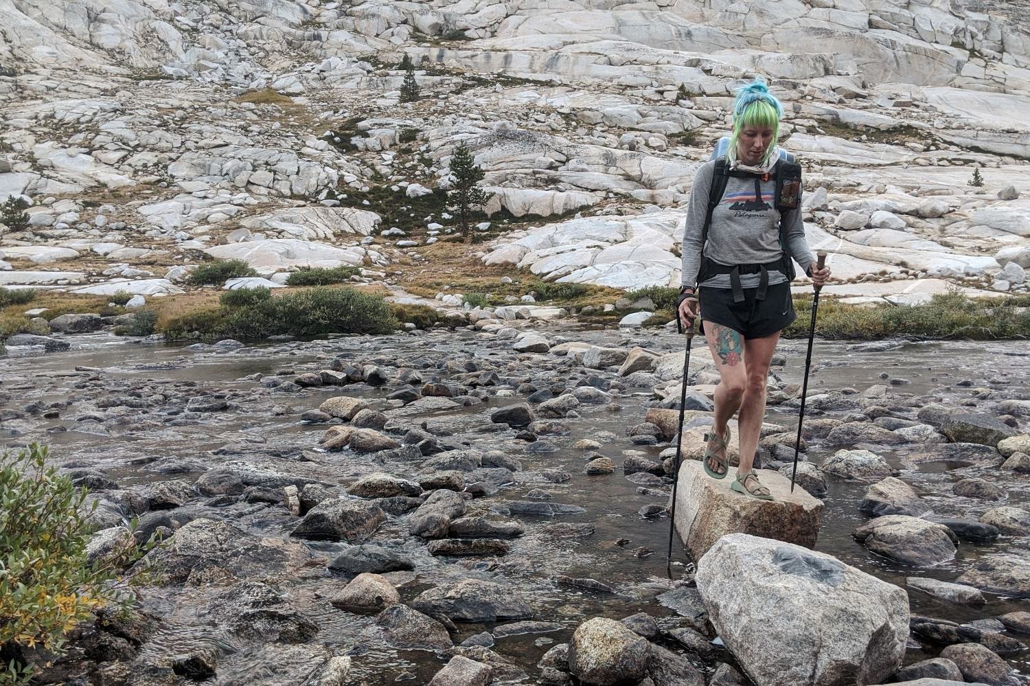 A hiker crossing a river in Nike Dri-FIT Tempo shorts