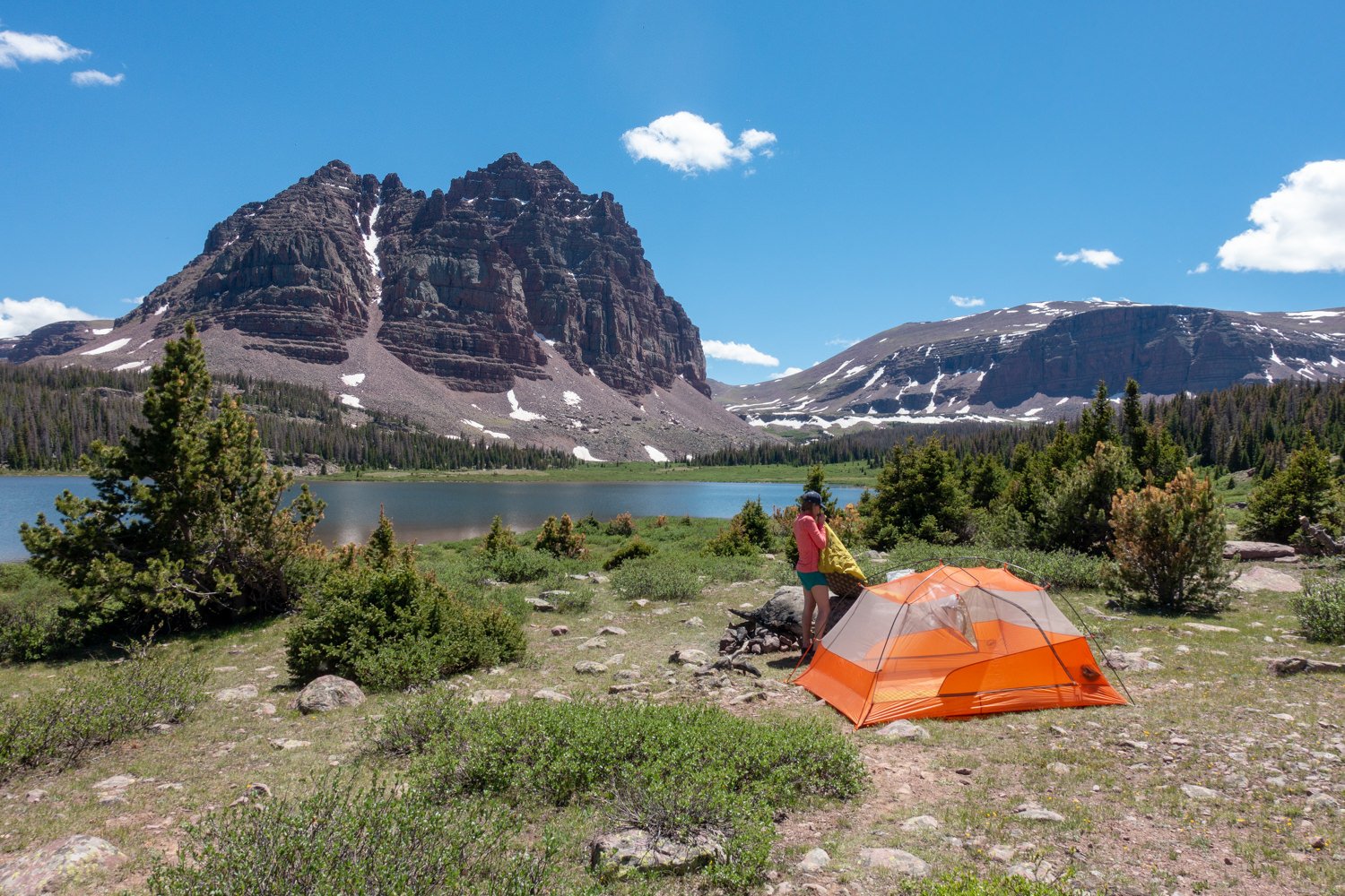 A backpacker inflating a sleeping pad in a beautiful campsite