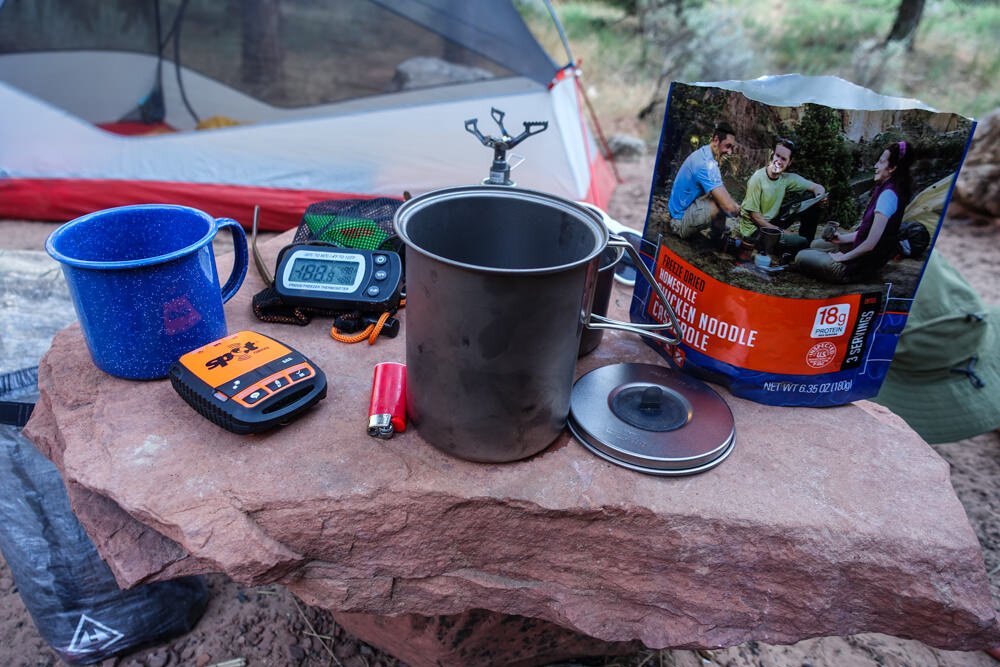 A backpacking cook system and a freeze dried meal sitting on a rock