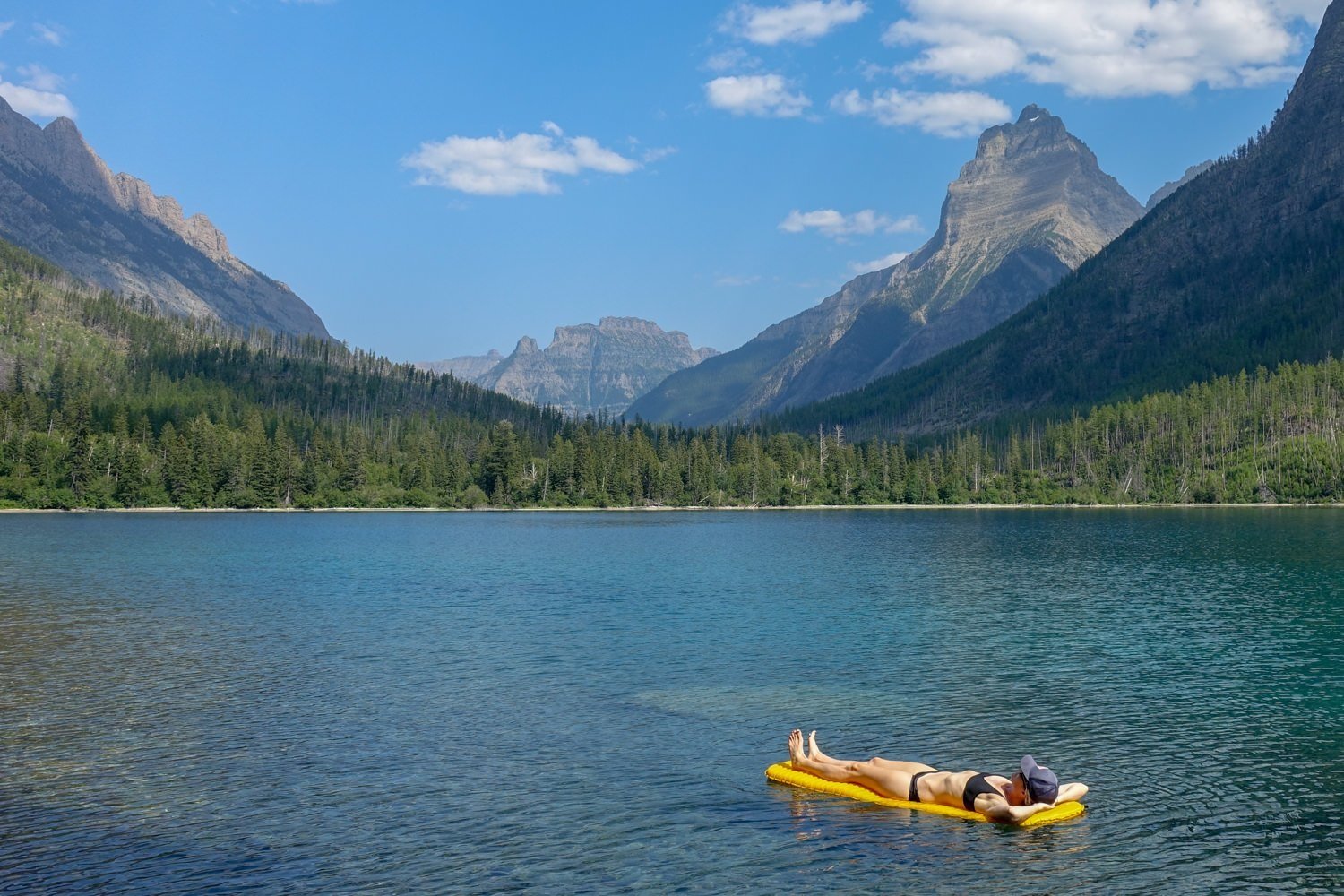 A backpacker floating on a lake in Glacier National Park on the NEMO Tensor Sleeping Pad