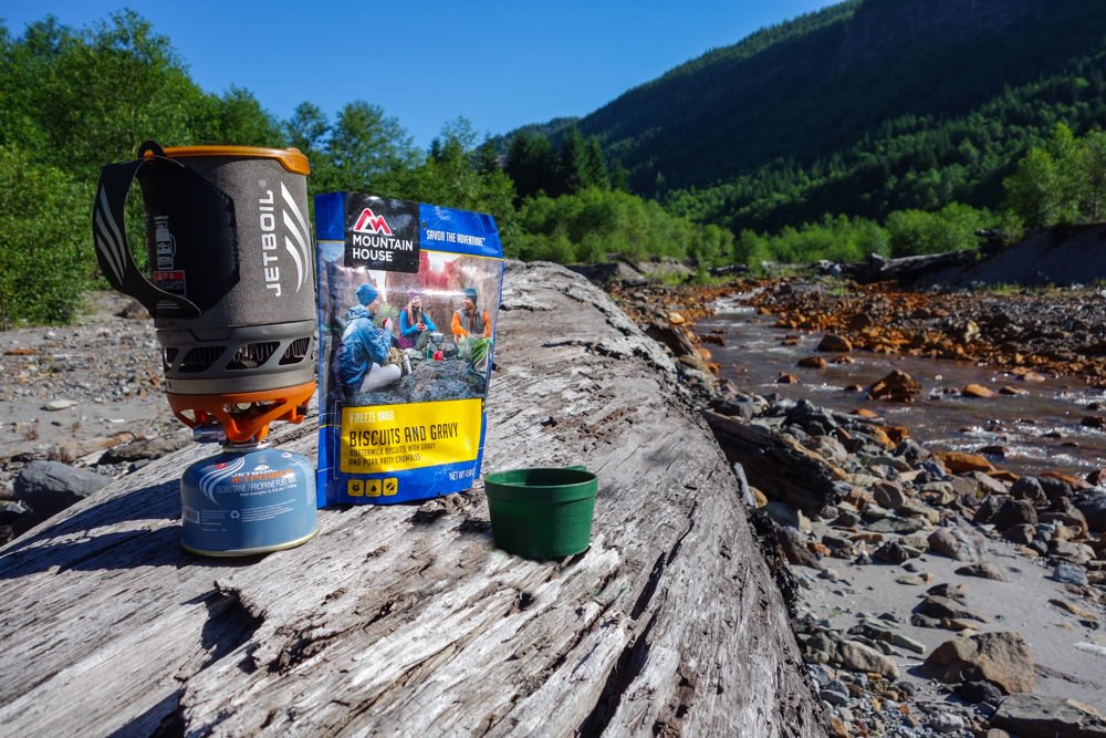 The Jetboil Flash stove and Mountain house Biscuits and Gravy sitting on a rock in front of a river