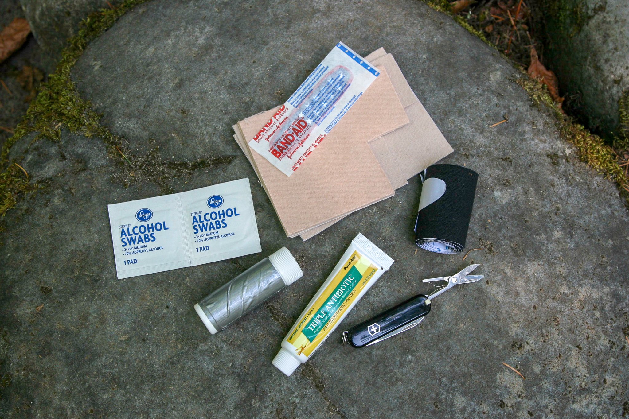 Top-down view of first aid supplies on a rock including the Swiss Army Classic multitool