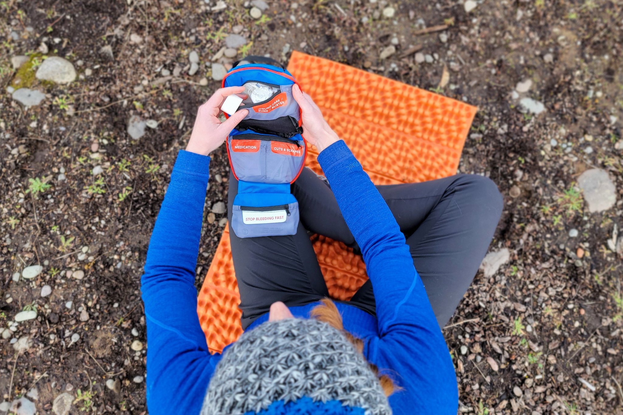 Top-down view of a hiker getting supplies from a pocket of the Adventure Medical Kits Hiker First Aid Kit