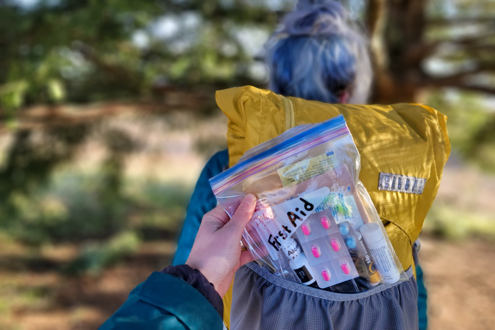 Closeup of a hand pulling a custom DIY first aid kit from a hiker's backpack