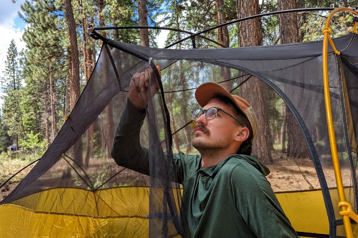 A hiker closing the zippered door of the REI Flash 2 Tent with one hand