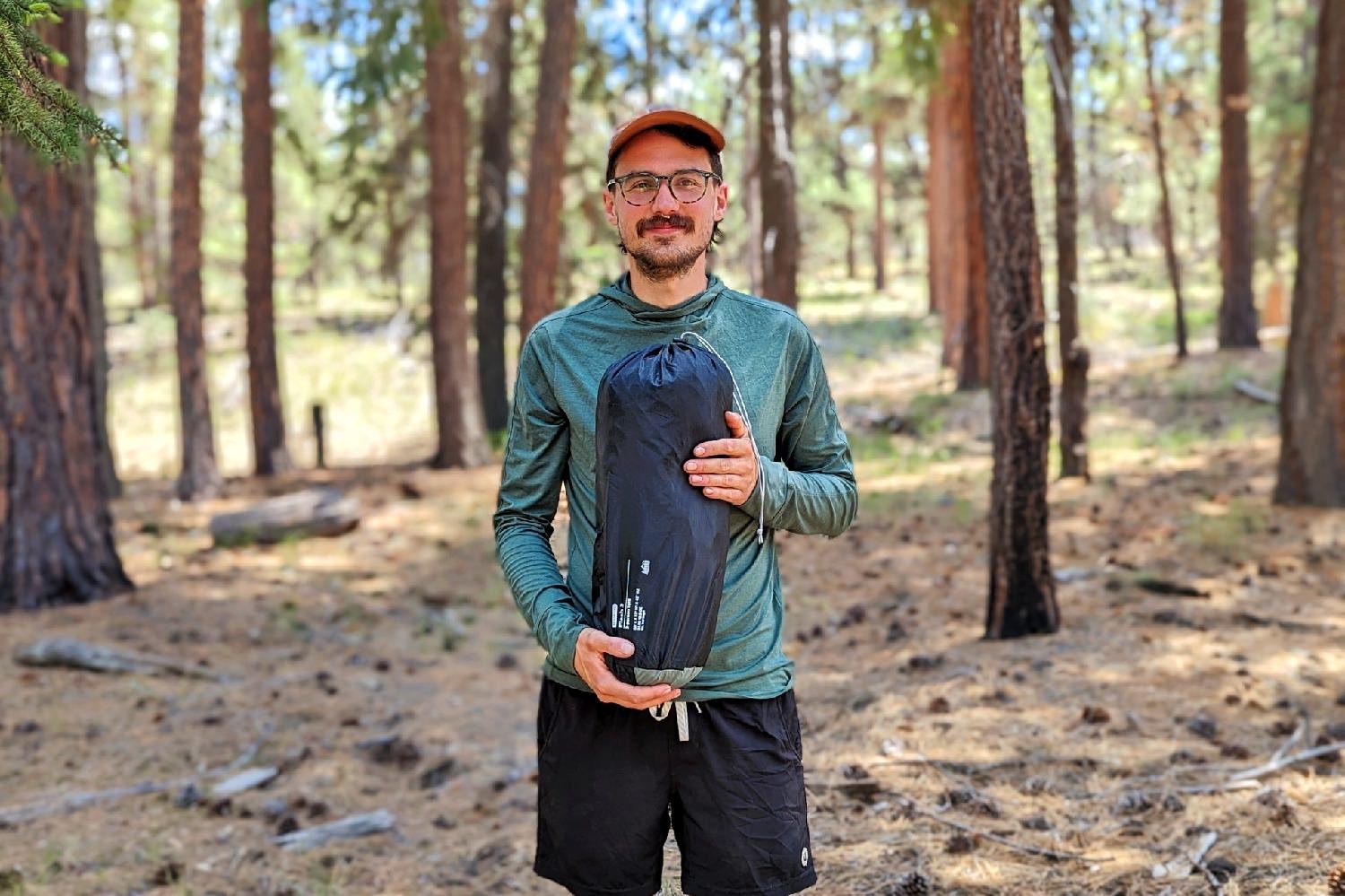 A hiker holding the REI Flash 2 Tent in its stuff sack to show the packed size