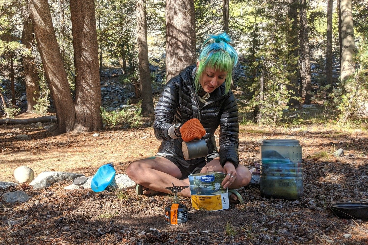 A hiker pouring water into a freeze dried meal from backpackers pantry