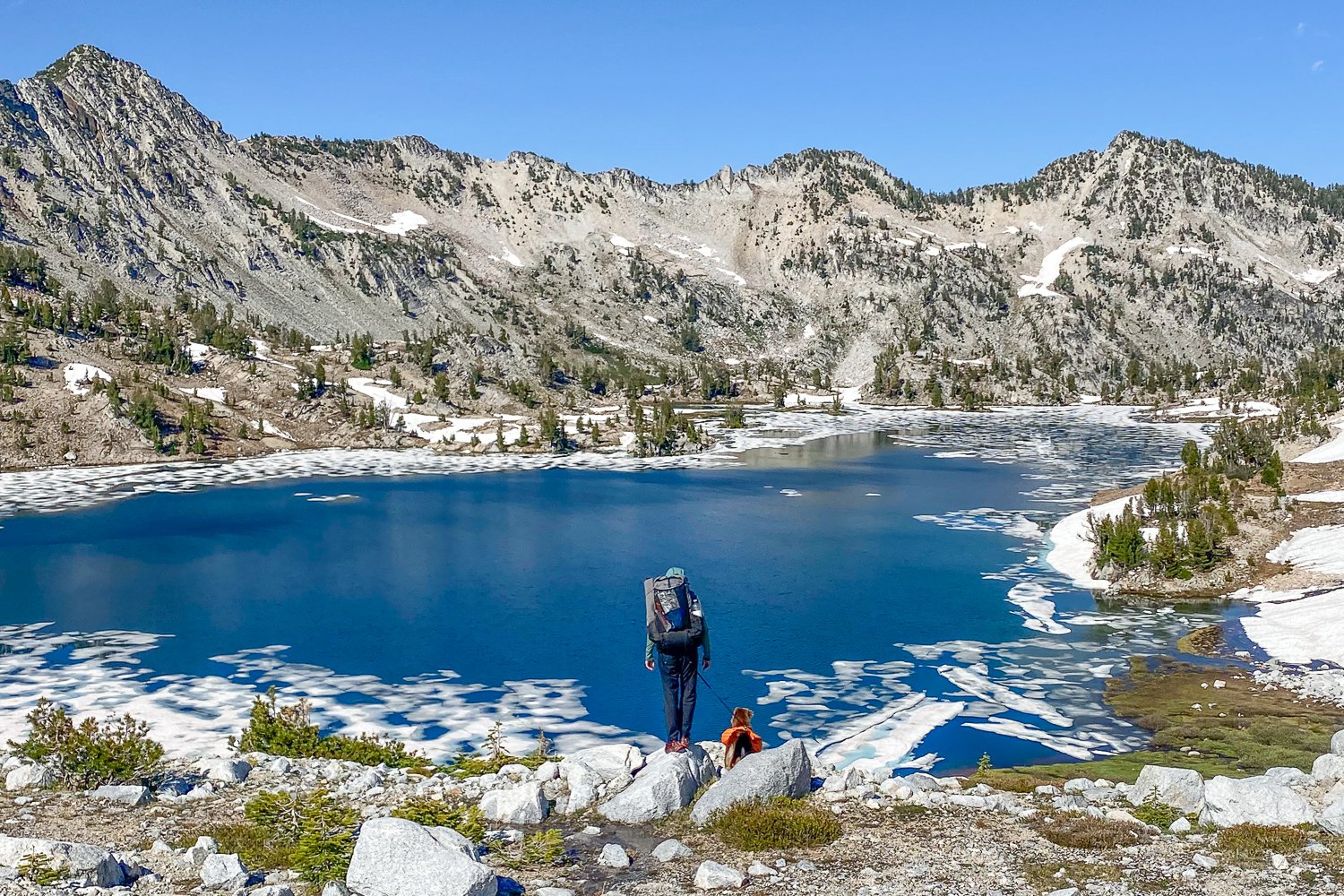 A backpacker and her dog standing in front of a high alpine lake with the Zpacks Arc Haul Ultra backpack