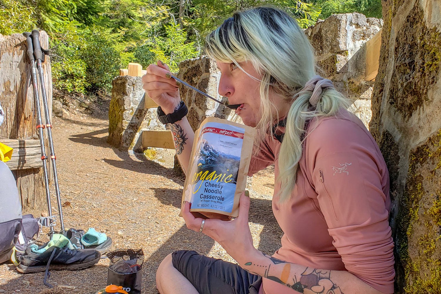 A hiker eating a freeze dried meal from Mary Janes Farm on a trail