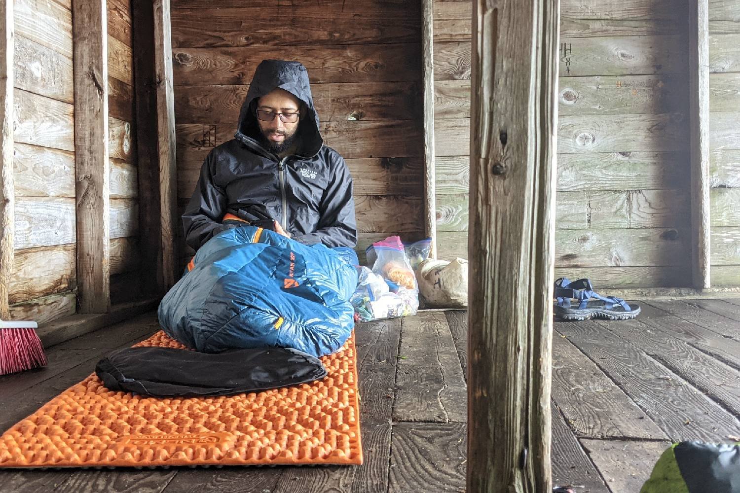 A hiker sitting on the NEMO Switchback sleeping pad inside of a trail shelter