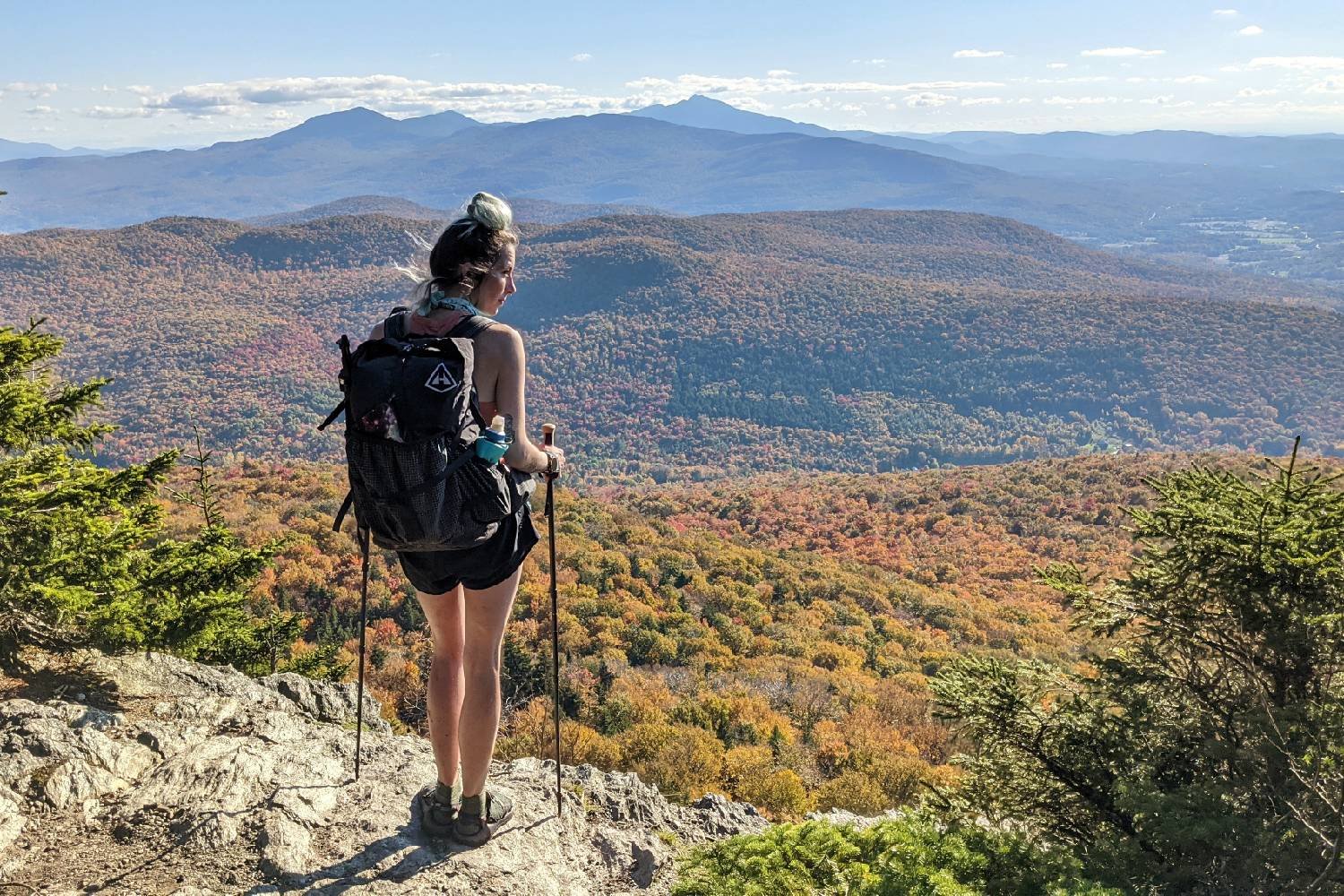 A hiker standing on a ledge with the Gossamer Gear LT5 trekking poles looking at a mountain view