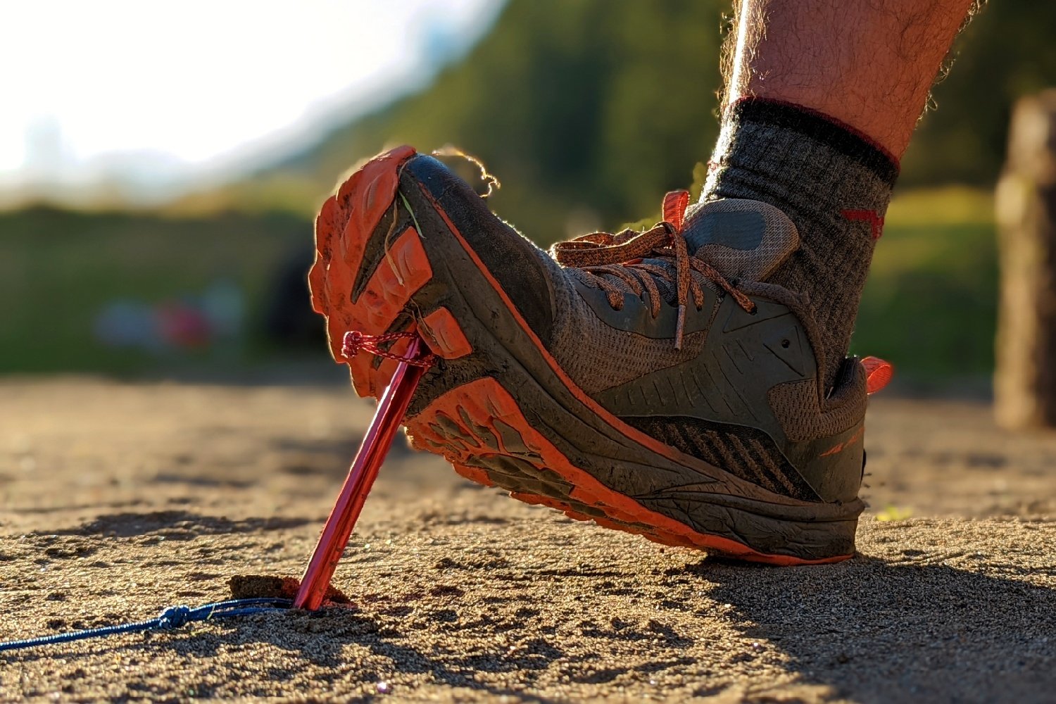 A hiker pushing an MSR Mini Groundhog Tent Stake into the ground with their shoe