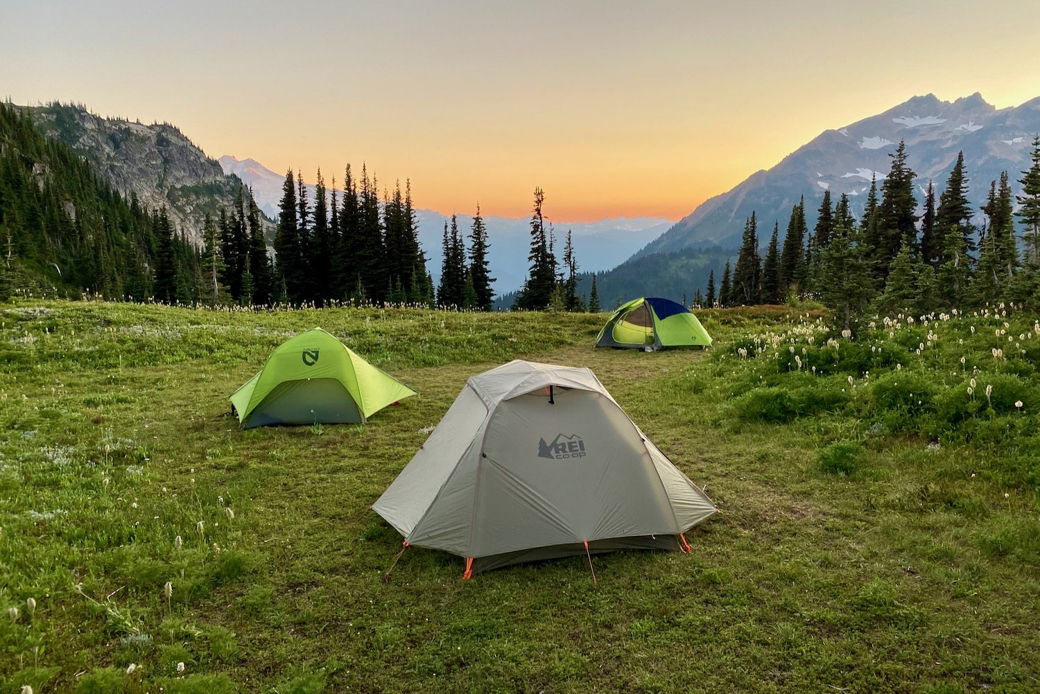 three tents on a high ridge with mountains in the distant scenery