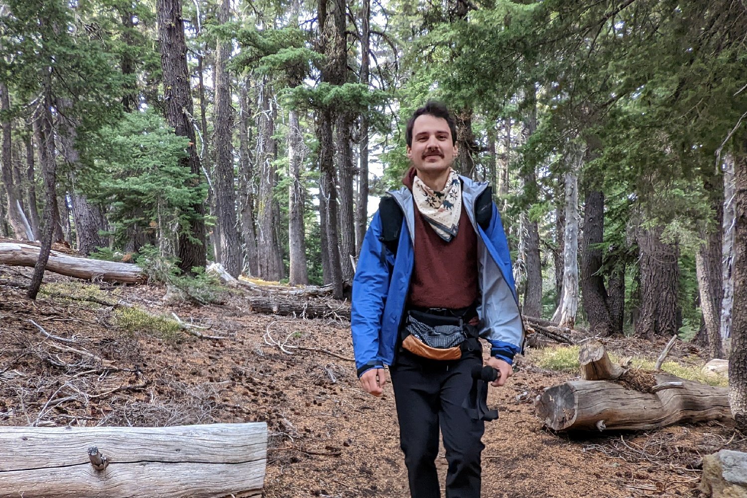 A hiker walking down a trail wearing the Thru Pack Summit Bum Fanny Pack