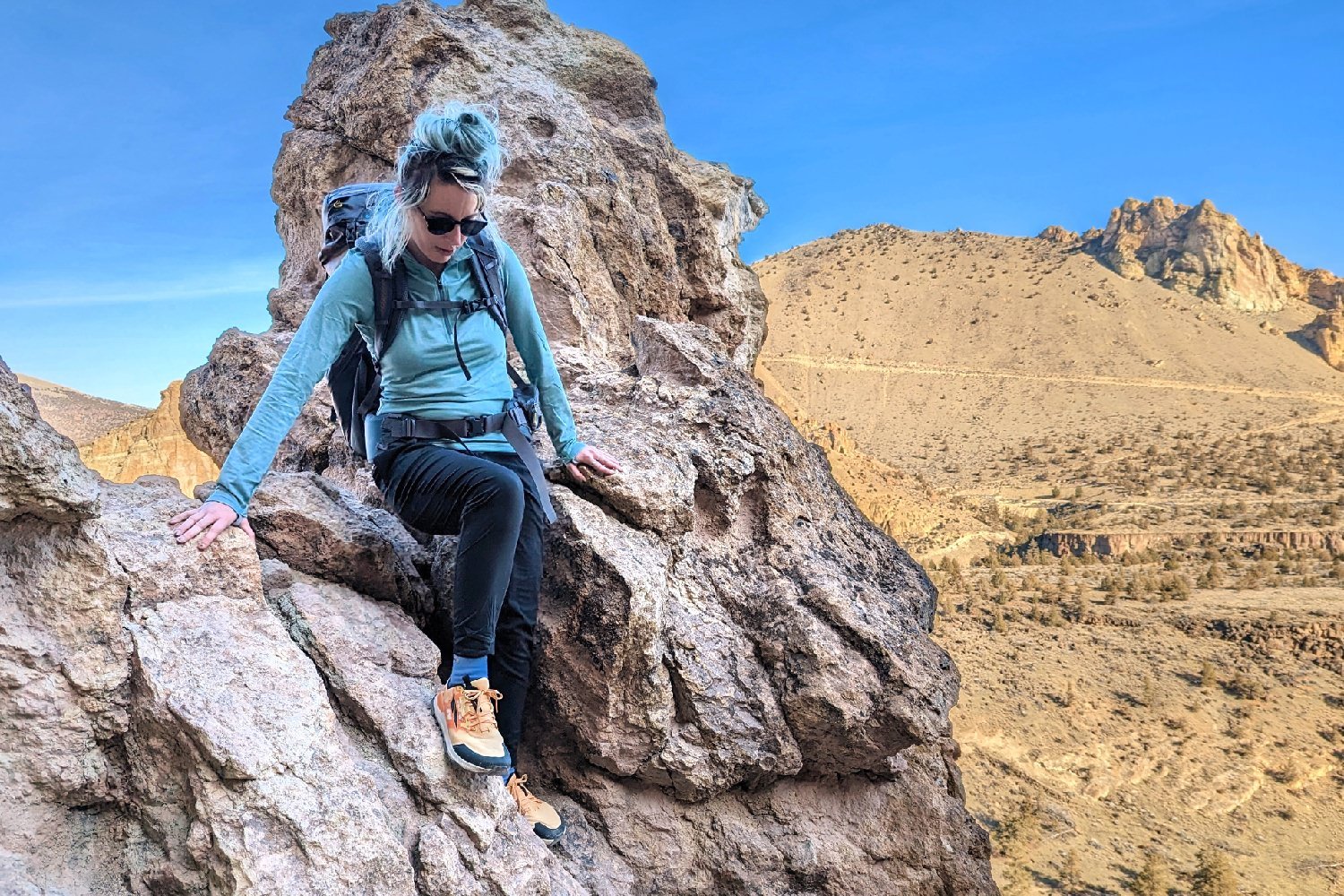 A hiker scrambling down some rocks in a desert scene