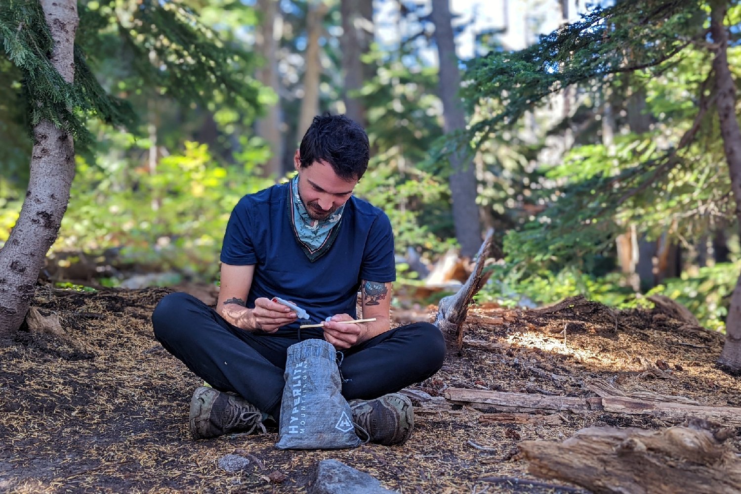 A hiker sitting in the woods with a Hyperlite Mountain Gear Drawstring Stuff Sack in front of him