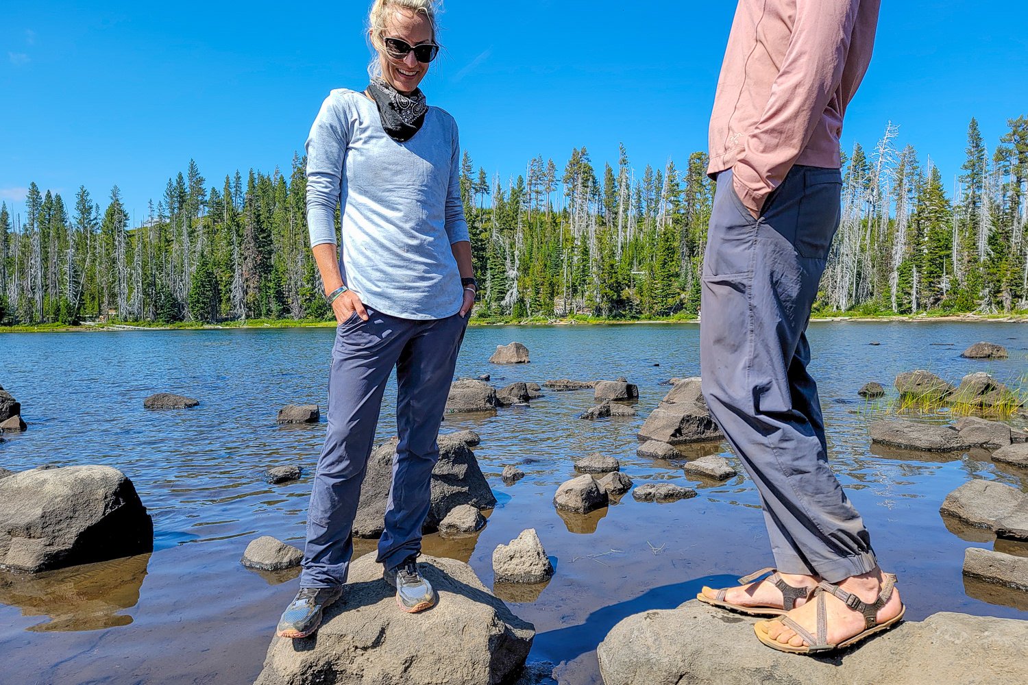 Two hikers standing on rocks next to a lake