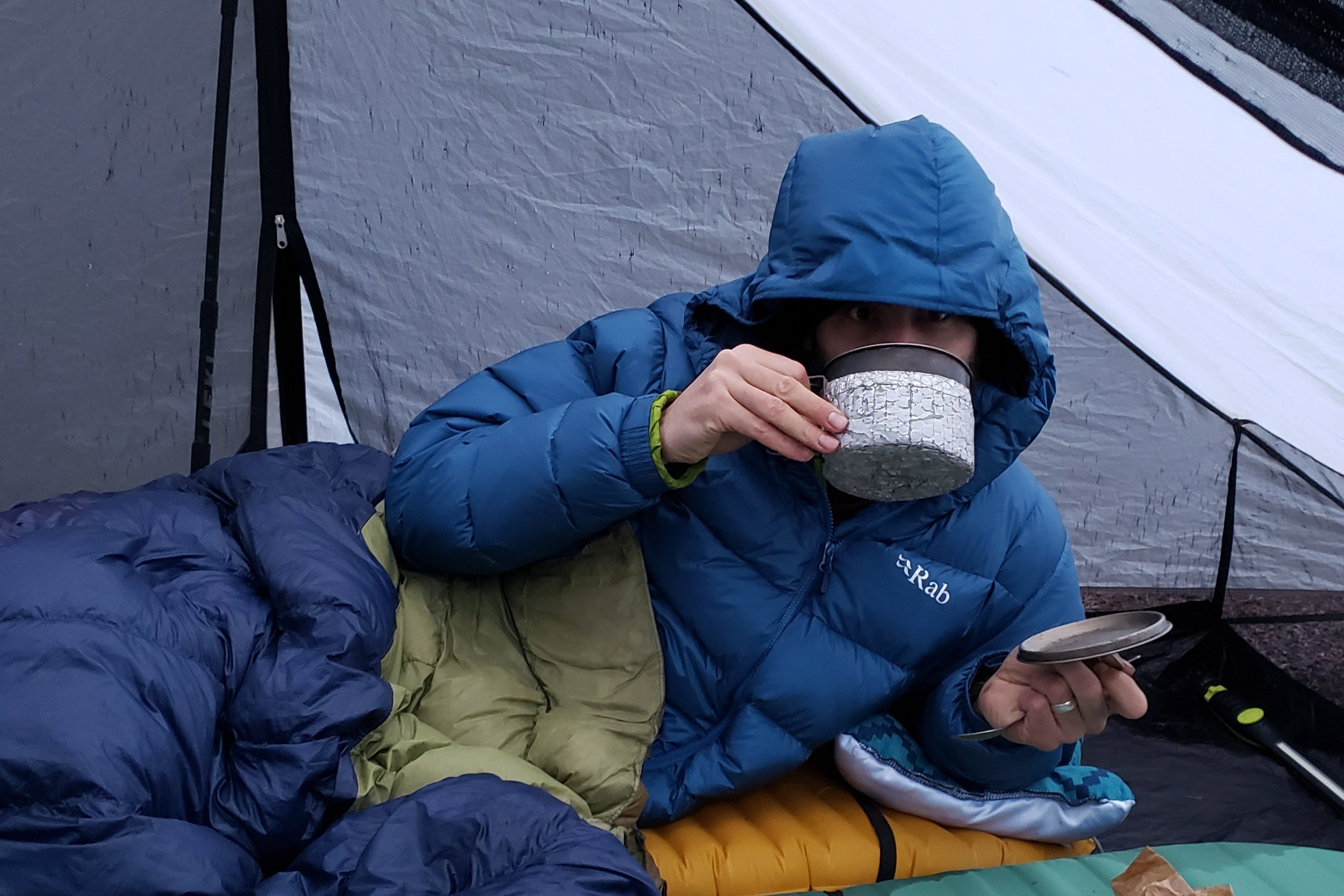 A backpacker wearing the Rab Neutrino Pro jacket in camp